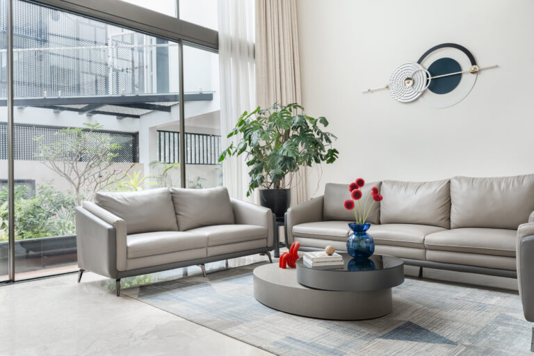 A spacious modern living room featuring designer furniture and a neutral color palette with gold accents.