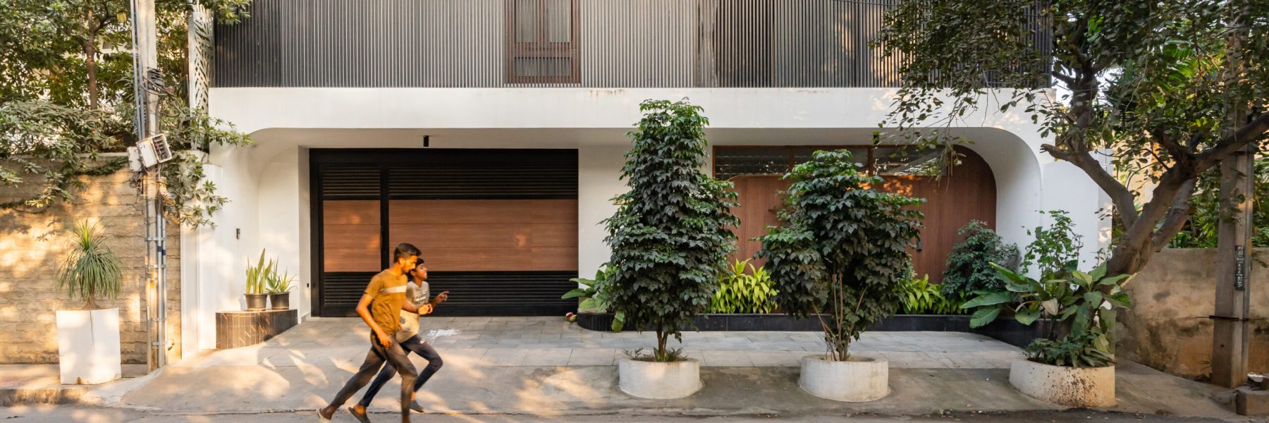 The front facade of a contemporary villa showcasing a mix of natural materials and geometric forms designed by A.P.E. Studios.